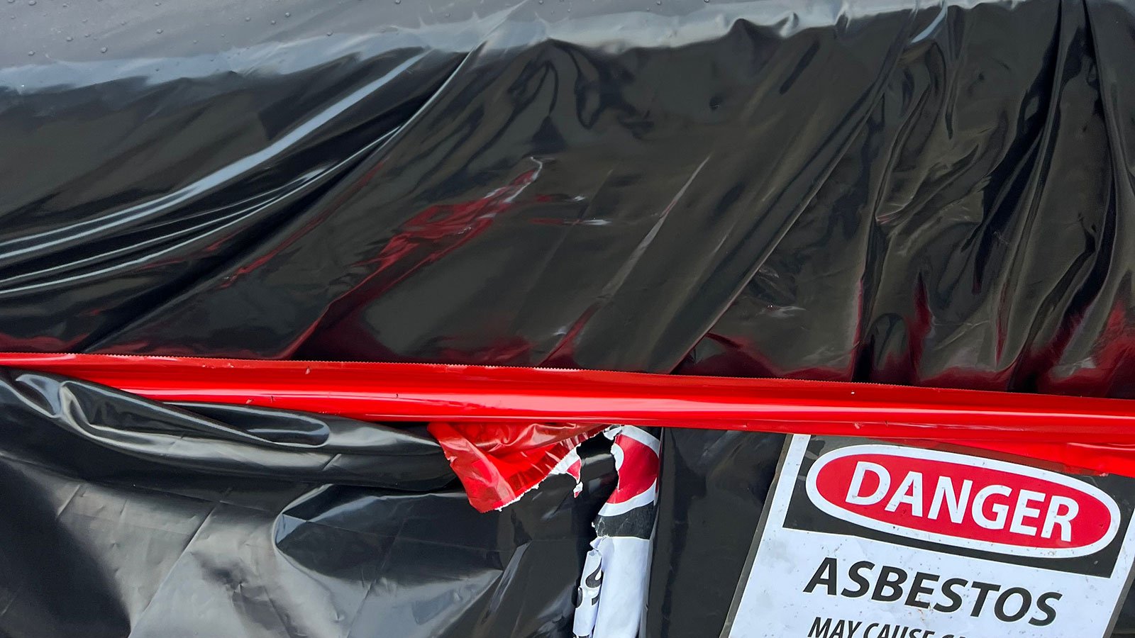 Asbestos containing material disposed of with warning sign.