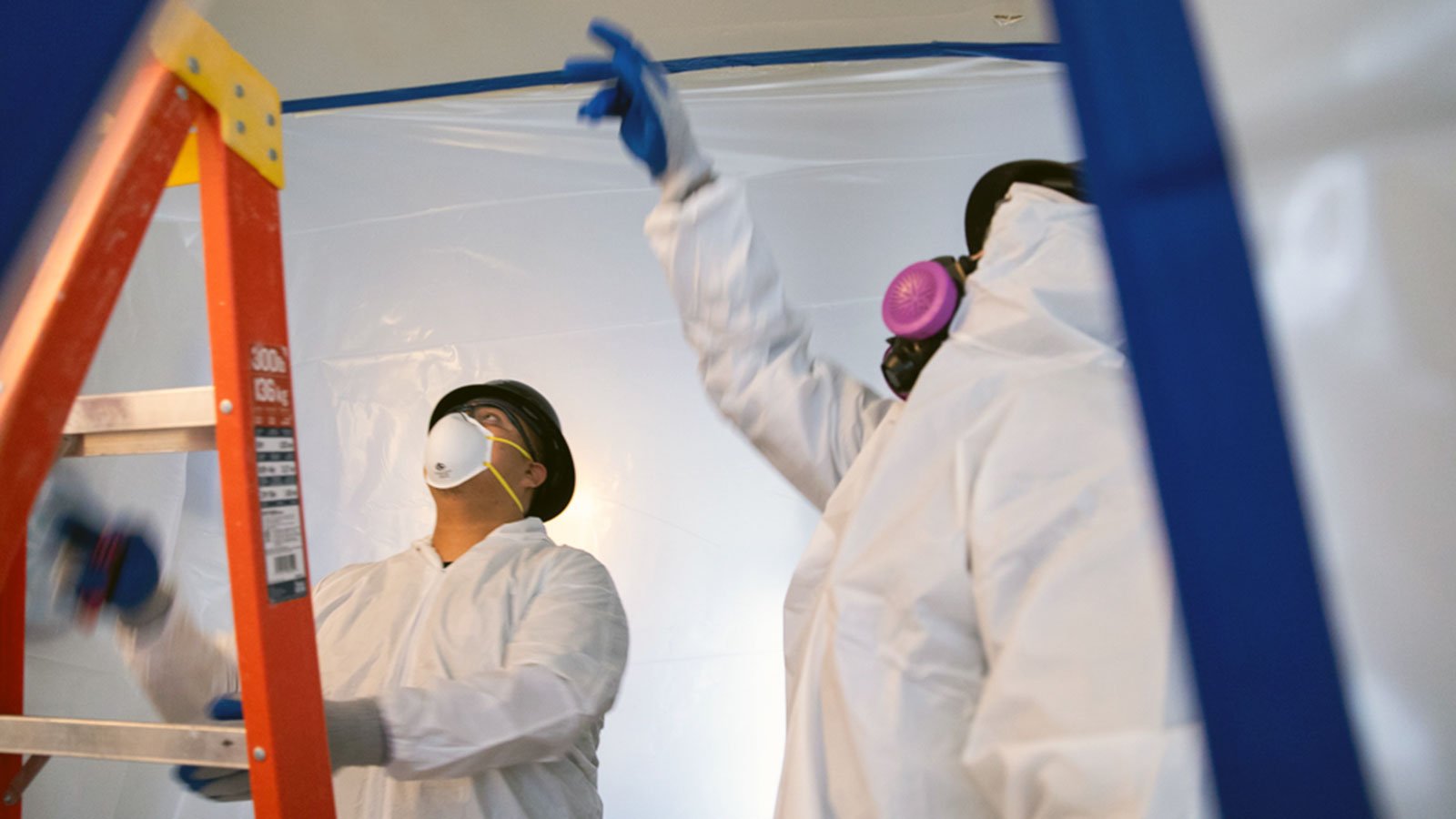 CRC team members pointing at ceiling in mold containment area